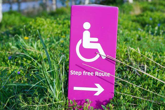 A pink accessibility sign that reads "Step-free Route" lays in the grass.